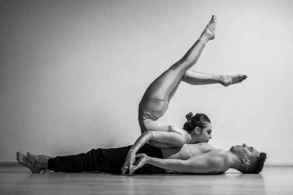 Un duo d'acrobates montrant un tour de paire. Une femme en salopette de gymnastique dans un stand de main sur un homme torse nu se trouve sur le dos. Artistes de cirque très flexibles. — Photo