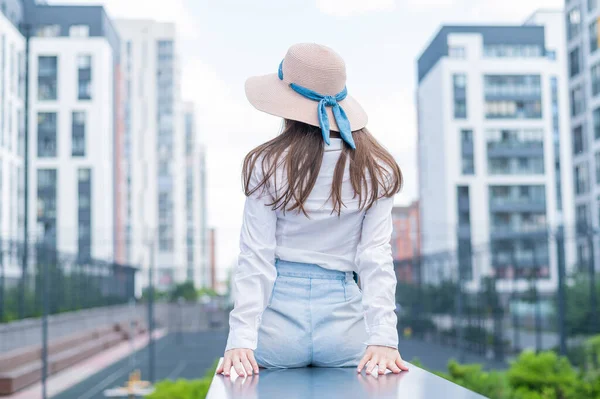 Vista trasera de una mujer en un sombrero sentado en el fondo de la ciudad —  Fotos de Stock