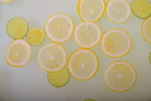 Turbid soapy water in the bath with slices of lemon and lime top view in full frame. Citrus. Spa with milk in the bath for rejuvenation. — Stock Photo, Image