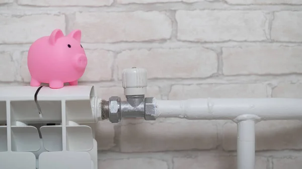 A piggy bank piggy bank on a radiator on a brick wall background
