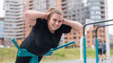 Spor sahasında egzersiz makineleri üzerinde egzersiz yapan şişman genç bir kadın..