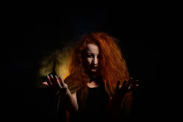 Egy gonosz vörös hajú boszorkány tüzet tart a kezében.. — Stock Fotó