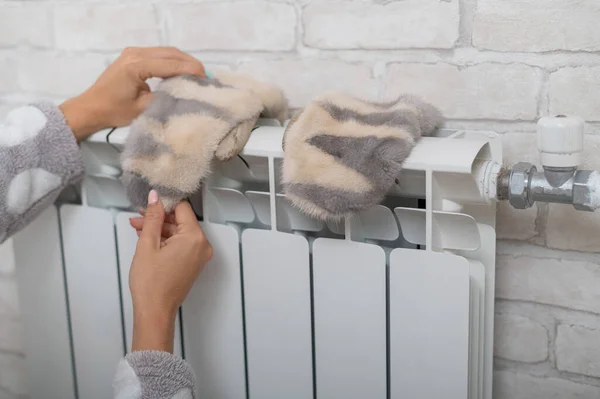 Een vrouw droogt handschoenen op een radiator. — Stockfoto