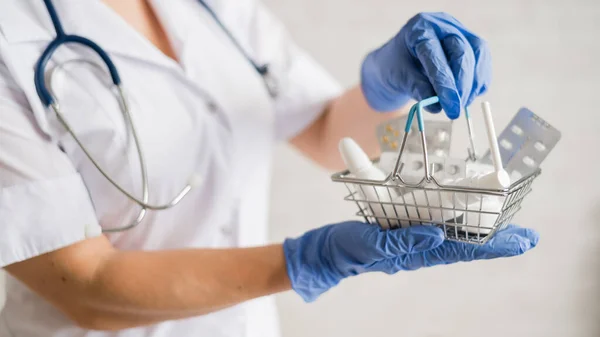 Uma médica feminina sem rosto segura uma mini cesta com medicamentos — Fotografia de Stock