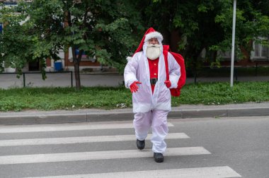 Noel Baba koruyucu takım elbise giymiş yaya geçidinde yürüyor.