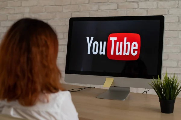 September 16, 2020 Russia, Novosibirsk: Rear view of a woman sitting at a computer with the YouTube logo on the monitor. — Stock Photo, Image