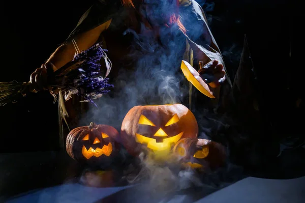 魔女はハロウィンの暗闇の中で蒸しカボチャに呪文を投げます — ストック写真