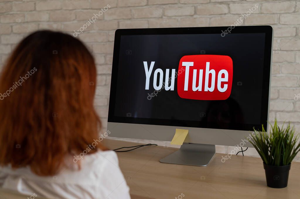 September 16, 2020 Russia, Novosibirsk: Rear view of a woman sitting at a computer with the YouTube logo on the monitor