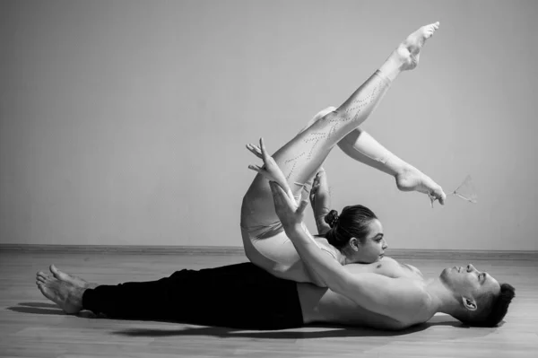 Pesada pose de circo. Un joven sostiene a una mujer flexible. Dos acróbatas o bailarines posando sobre un fondo blanco. Un par de gimnastas realizan arte. —  Fotos de Stock