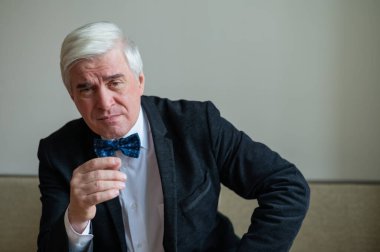 Takım elbiseli yaşlı bir adam parmağını gösterir..