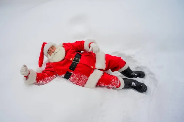 Heureux Père Noël claus couché dans la neige et de s'amuser autour — Photo