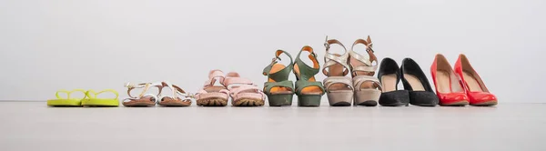 Uma variedade de sapatos femininos diversificados em um fundo branco. Widescreen foto. — Fotografia de Stock