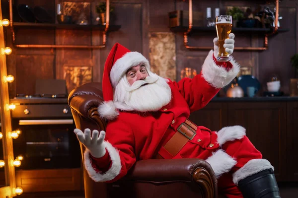 Santa Claus drinks beer while sitting in a leather armchair — Stock Photo, Image