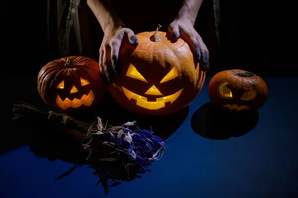 Zbliżenie żeńskie ręce trzymając halloween dynia w ciemności — Zdjęcie stockowe