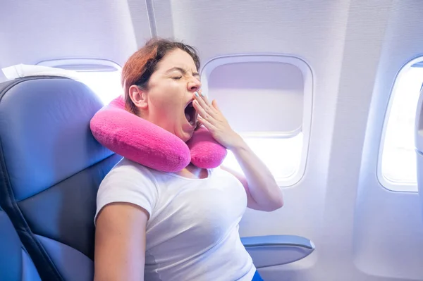 Mujer bosteza mientras está sentado en el avión por la ventana. — Foto de Stock