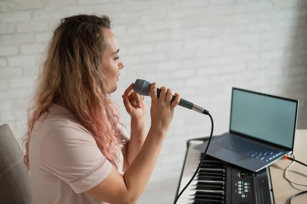 Eine Frau singt in ein Mikrofon und dreht einen Videoblog auf einem Laptop — Stockfoto