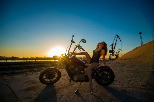 Rödhårig kvinna i sexiga underkläder i höga klackar sitter på en motorcykel. Attraktiv rödhårig flicka sitter på en motorcykel vid solnedgången — Stockfoto