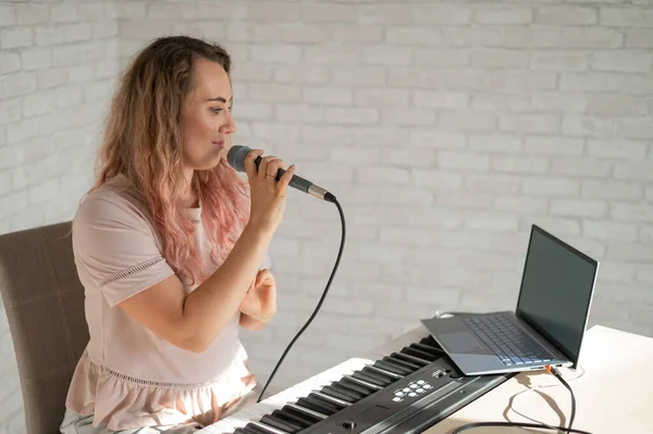 Een vrouw zingt in een microfoon en schiet een video blog op een laptop — Stockfoto