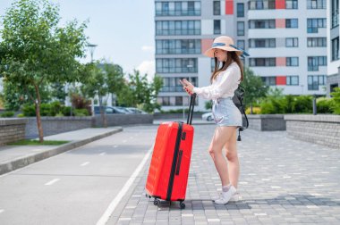 Beyaz bir kadın kırmızı bir bavulla sokakta yürüyordu..