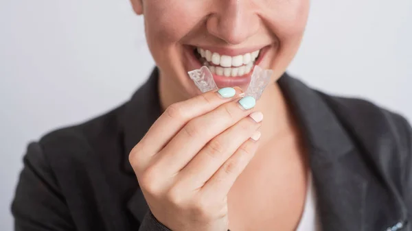 İş kadını dişlerini beyazlatmak için şeffaf diş teli kullanıyor.