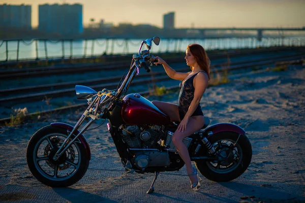 Donna dai capelli rossi in lingerie sexy con tacchi alti si siede su una moto — Foto Stock