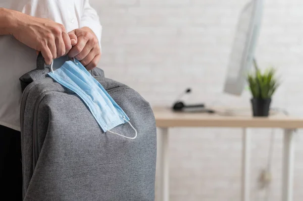 Mujer de negocios sosteniendo una mochila y una máscara médica — Foto de Stock