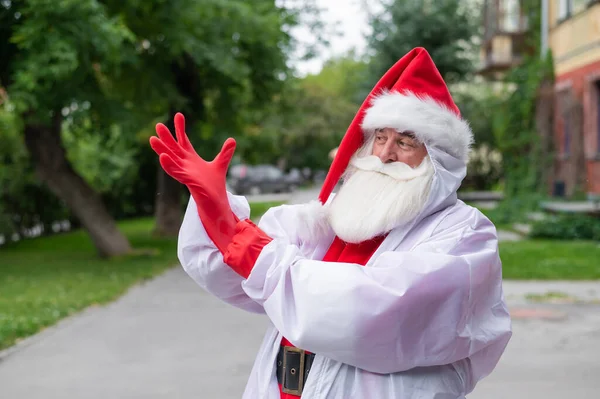 Santa claus i en skyddande kostym sätter på handskar. — Stockfoto