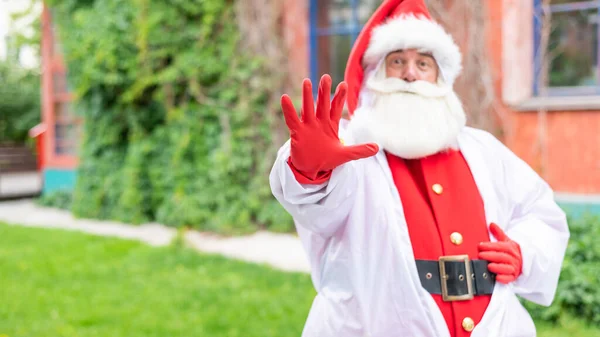 Der Weihnachtsmann im Schutzanzug zeigt mit der Handfläche eine Stoppgeste. Stoppt die Ausbreitung des Coronavirus — Stockfoto