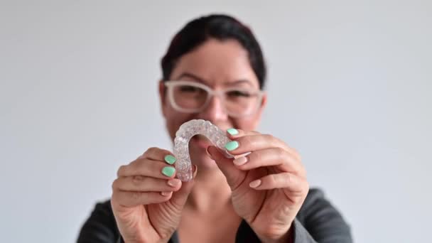 De vrouw glimlacht en houdt een doorzichtig plastic orthodontisch apparaat voor bijtcorrectie vast — Stockvideo