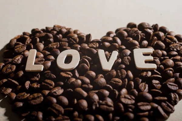 Großaufnahme von Kaffeebohnen in Herzform und der Aufschrift Liebe — Stockfoto