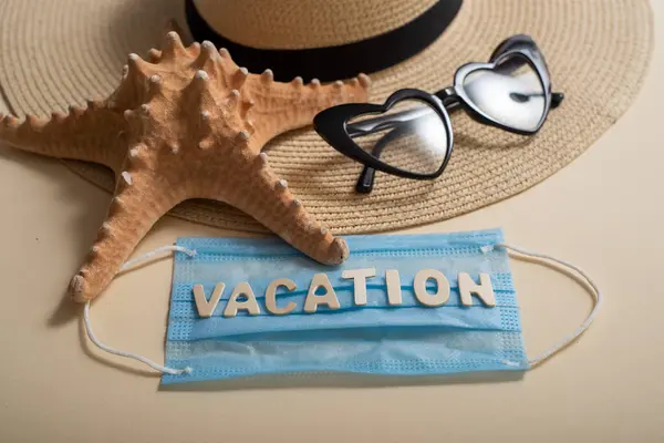 Vista superior de gafas de sol sombrero de paja estrella de mar y máscara con letras vacaciones. Concepto de viaje durante la propagación del coronavirus —  Fotos de Stock