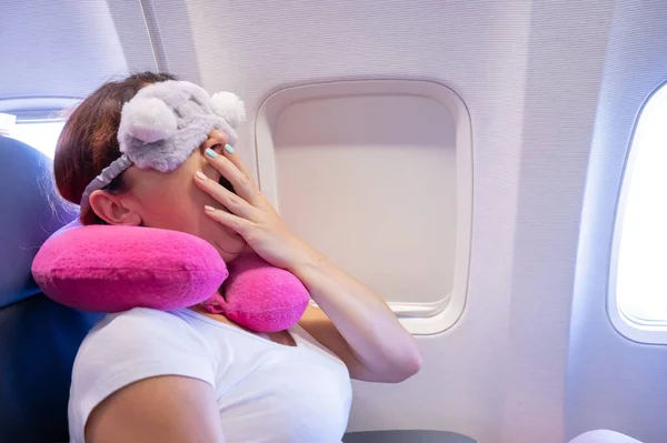 Mujer de pelo rojo cansada durmiendo en el avión con una máscara para los ojos y una almohada para el cuello — Foto de Stock