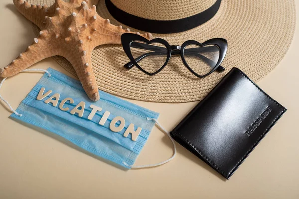 Gafas de sol sombrero de paja en forma de corazón, pasaporte, estrella de mar y máscara con las vacaciones de inscripción. Concepto de vacaciones en el mar durante una pandemia —  Fotos de Stock