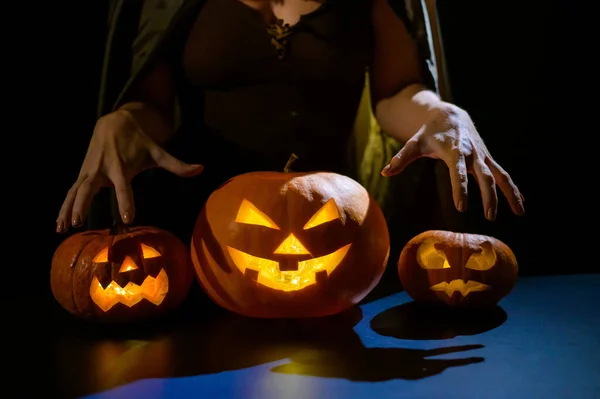 Zbliżenie żeńskich dłoni na dyni na Halloween w ciemnym studio. Czarownica trzyma latarnię. — Zdjęcie stockowe