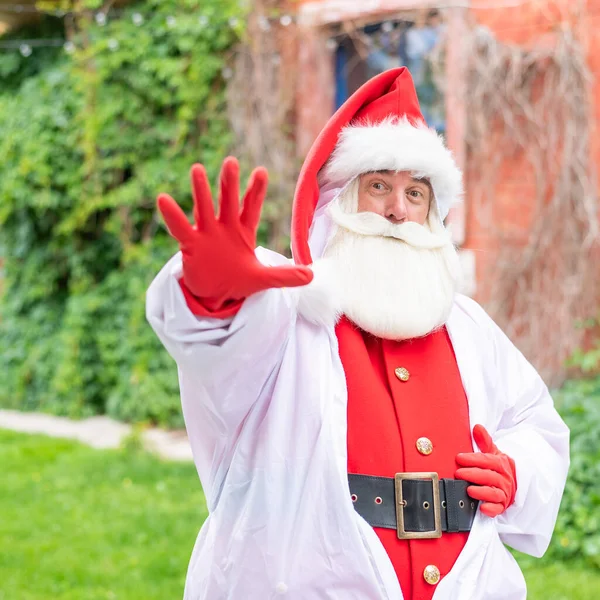 Der Weihnachtsmann im Schutzanzug zeigt mit der Handfläche eine Stoppgeste. Stoppt die Ausbreitung des Coronavirus — Stockfoto