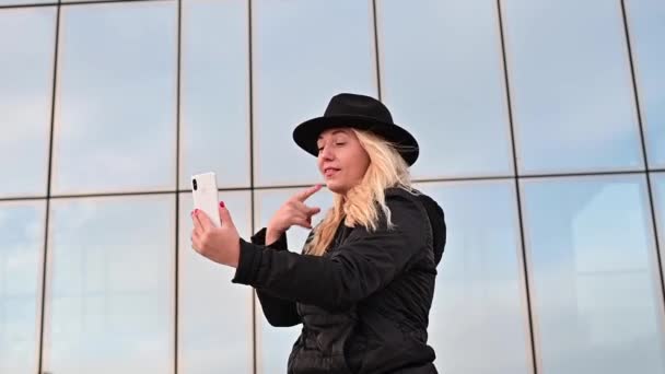 Mujer joven sordo-muda y habla el lenguaje de señas a través de la comunicación de vídeo en el teléfono al aire libre — Vídeos de Stock