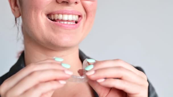 En kvinna använder transparenta tandställningar för att bleka tänderna — Stockvideo