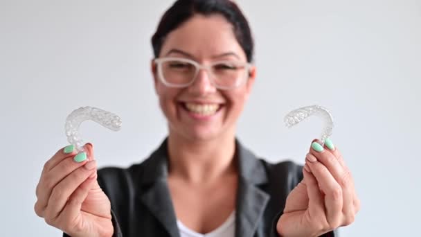 Caucasian woman holding two transparent heart-shaped aligners — Stock Video