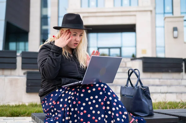 Ung kvinna talar teckenspråk på ett videosamtal på en bärbar dator utomhus. Den dövstumma flickan kommunicerar med gester — Stockfoto