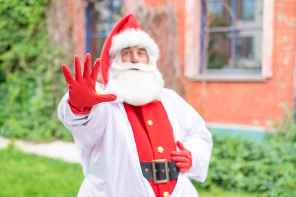 Der Weihnachtsmann im Schutzanzug zeigt mit der Handfläche eine Stoppgeste. Stoppt die Ausbreitung des Coronavirus — Stockfoto