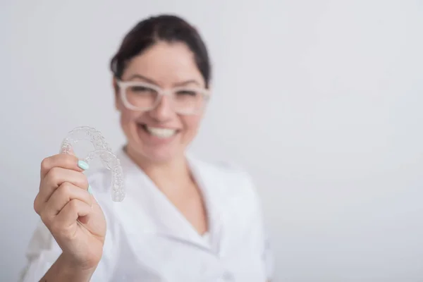 Une orthodontiste souriante tient deux aligneurs transparents. Le dentiste démontre le dispositif de correction des morsures — Photo