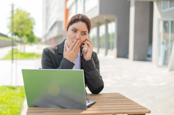 Affärskvinna pratar i telefon chockad av dåliga nyheter utomhus — Stockfoto
