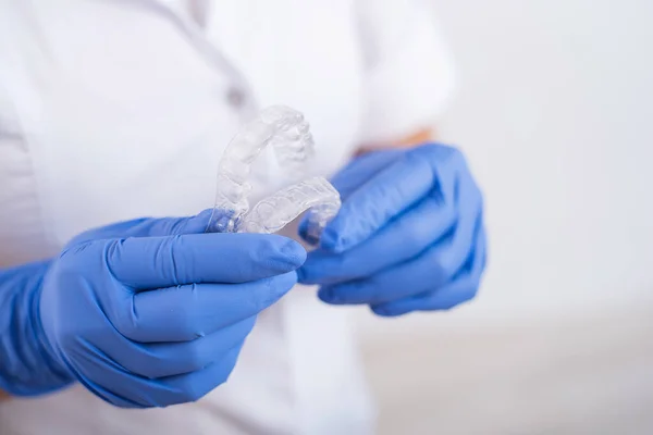 Uma ortodontista feminina sem rosto tem dois alinhadores transparentes. O dentista demonstra o dispositivo de correção de mordida — Fotografia de Stock