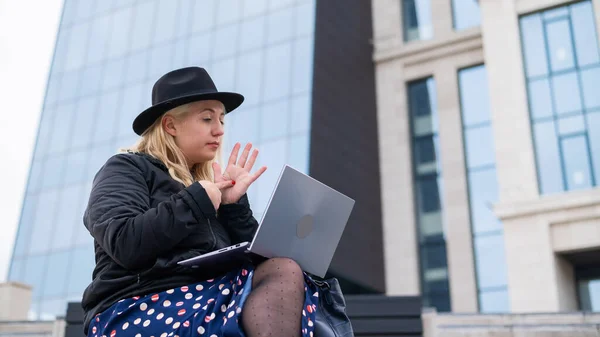 Ung kvinna talar teckenspråk på ett videosamtal på en bärbar dator utomhus. Den dövstumma flickan kommunicerar med gester — Stockfoto