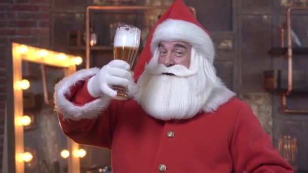 Święty Mikołaj gratuluje Bożego Narodzenia i pije szklankę piwa. — Wideo stockowe
