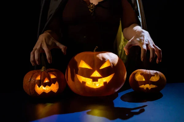 Zbliżenie żeńskich dłoni na dyni na Halloween w ciemnym studio. Czarownica trzyma latarnię. — Zdjęcie stockowe