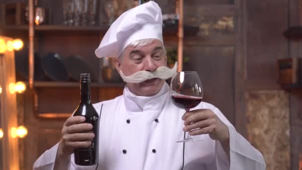Starszy szef kuchni zdegustował czerwone wino w kuchni — Wideo stockowe