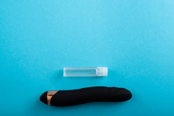 Top view of a black dildo and a bottle of lubricant on a blue background — Foto Stock