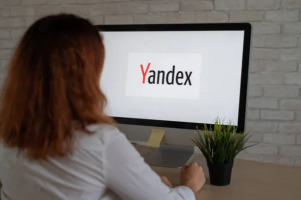 16 сентября 2020 года Россия, Новосибирск: взгляд сзади на женщину, сидящую за компьютером с логотипом "Яндекса" на мониторе. — стоковое фото
