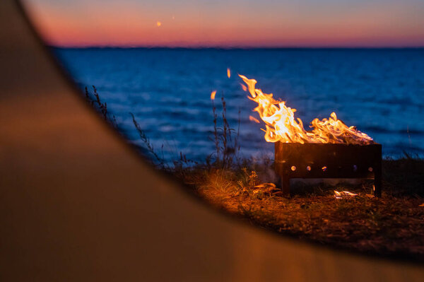 View from a tourist tent on bonfire on the seashore at sunset